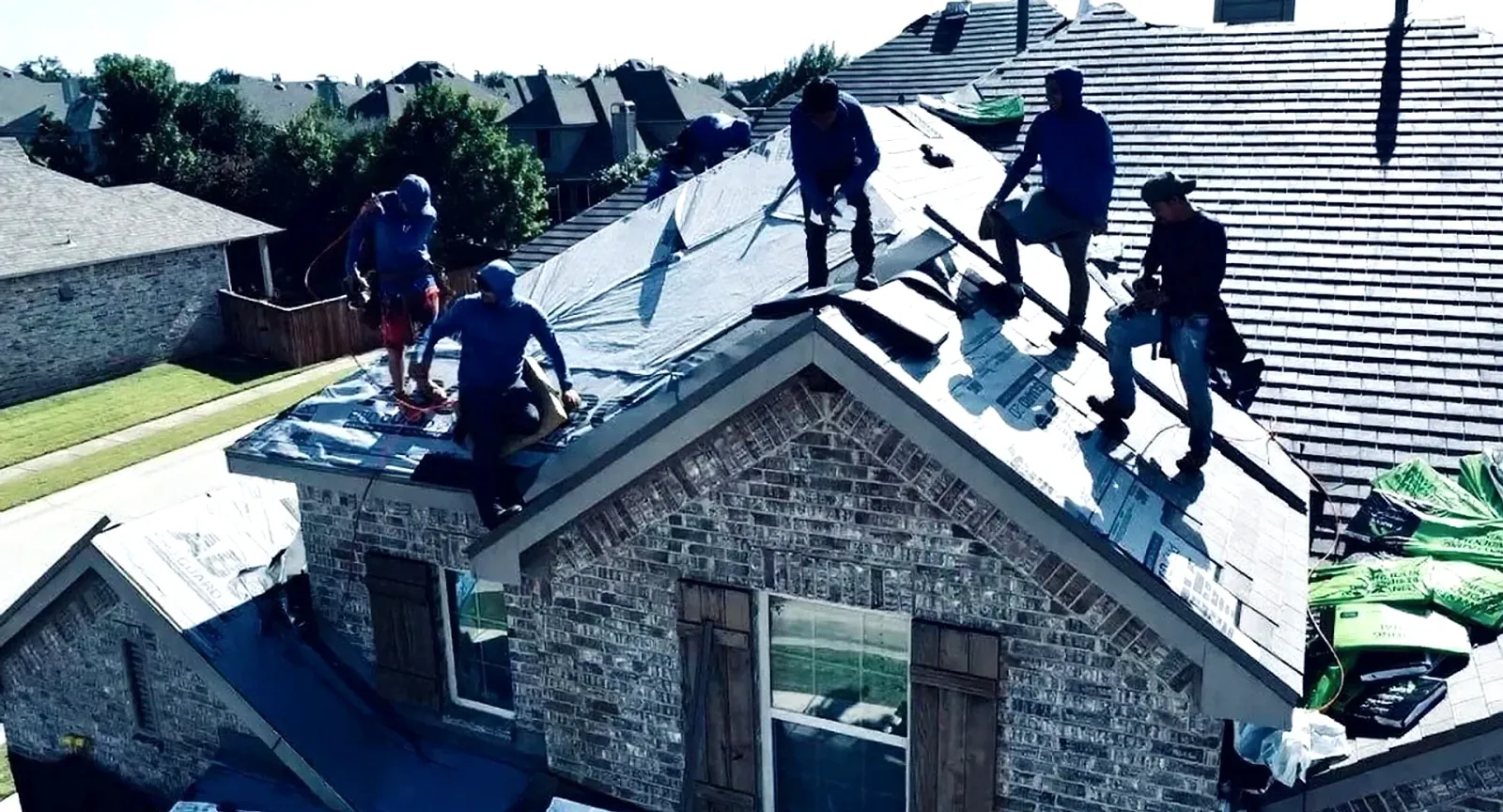 A roofing crew installing underlayment on a steep roof