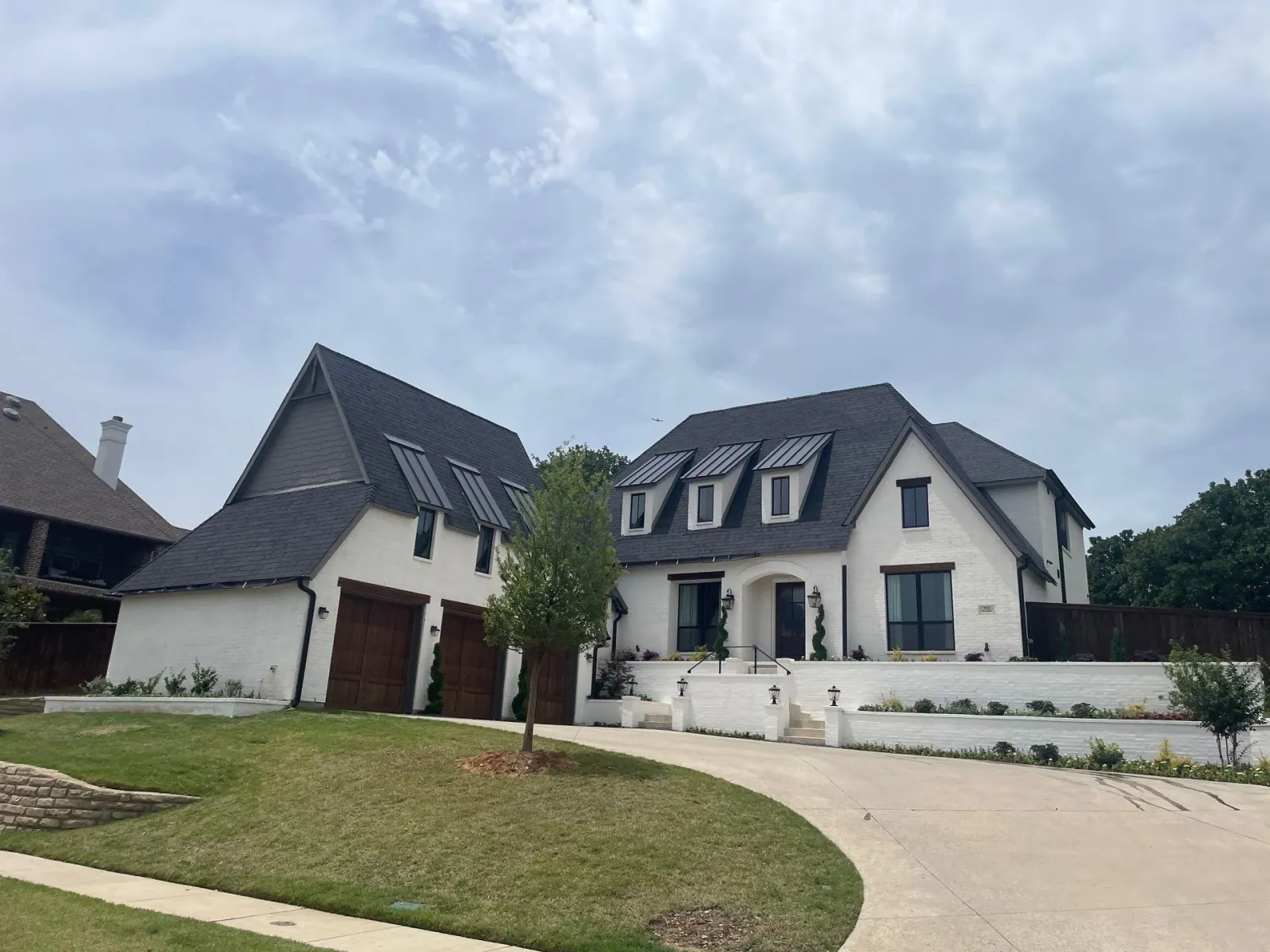 A finished home with a new charcoal shingle roof and black standing-seam metal accents by Compass Roofing