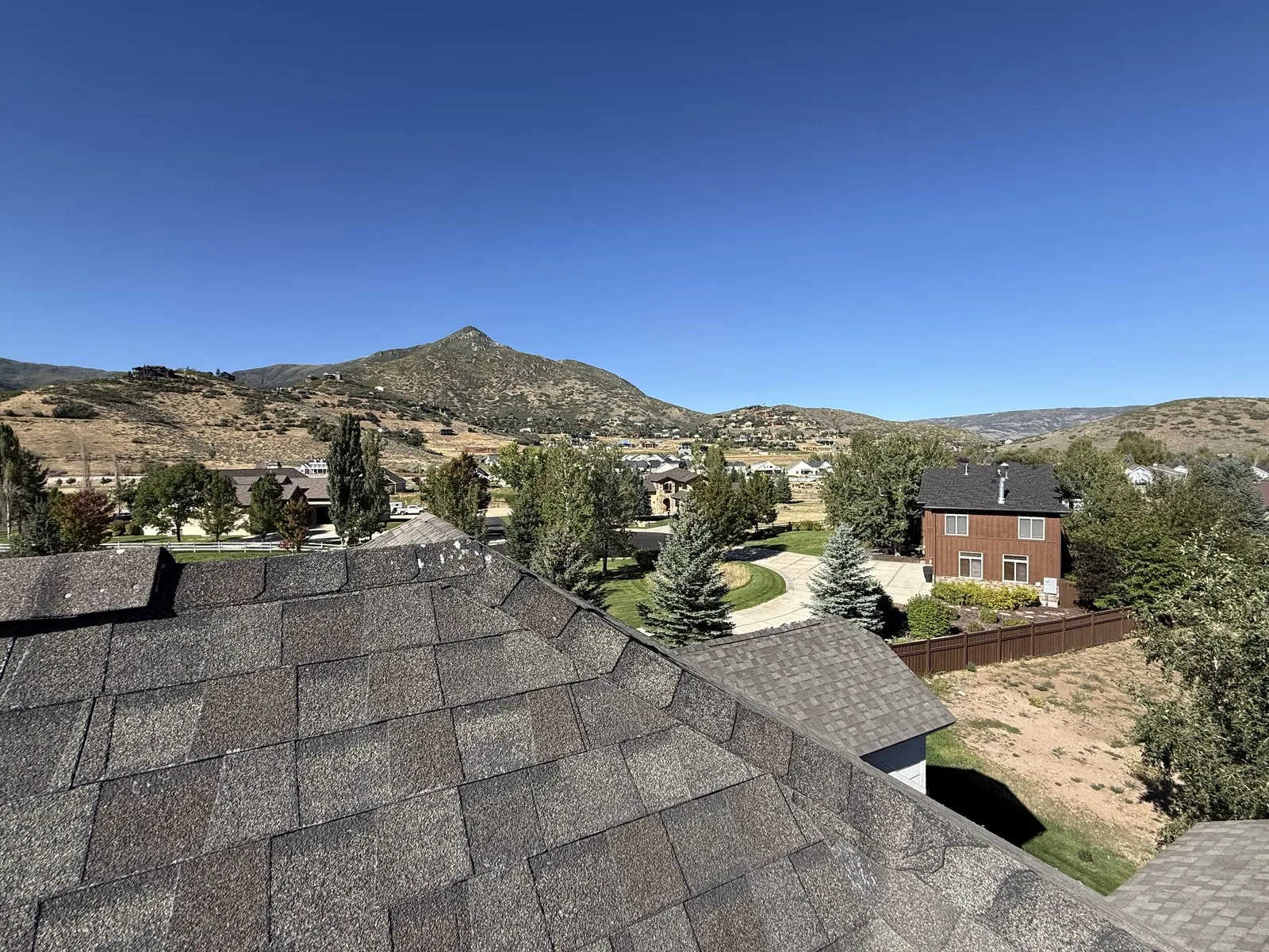 View from the ridge of an asphalt shingle roof in Midway, Utah, looking out across the Heber Valley toward the mountains